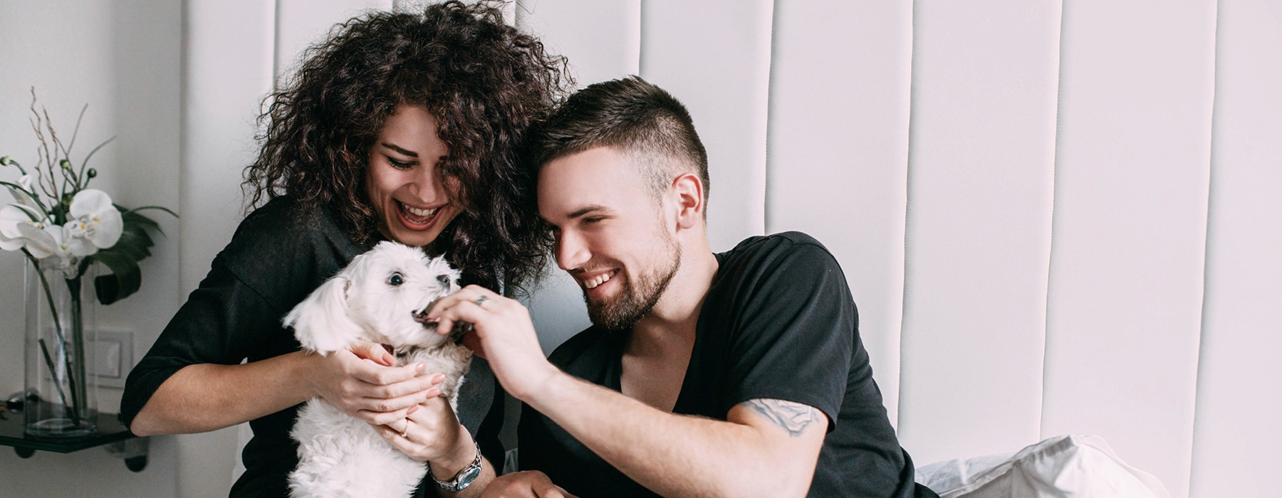 a young couple plays with their puppy in the bedroom