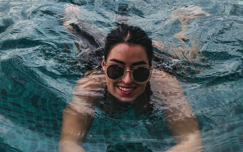 woman with sunglasses swimming in pool